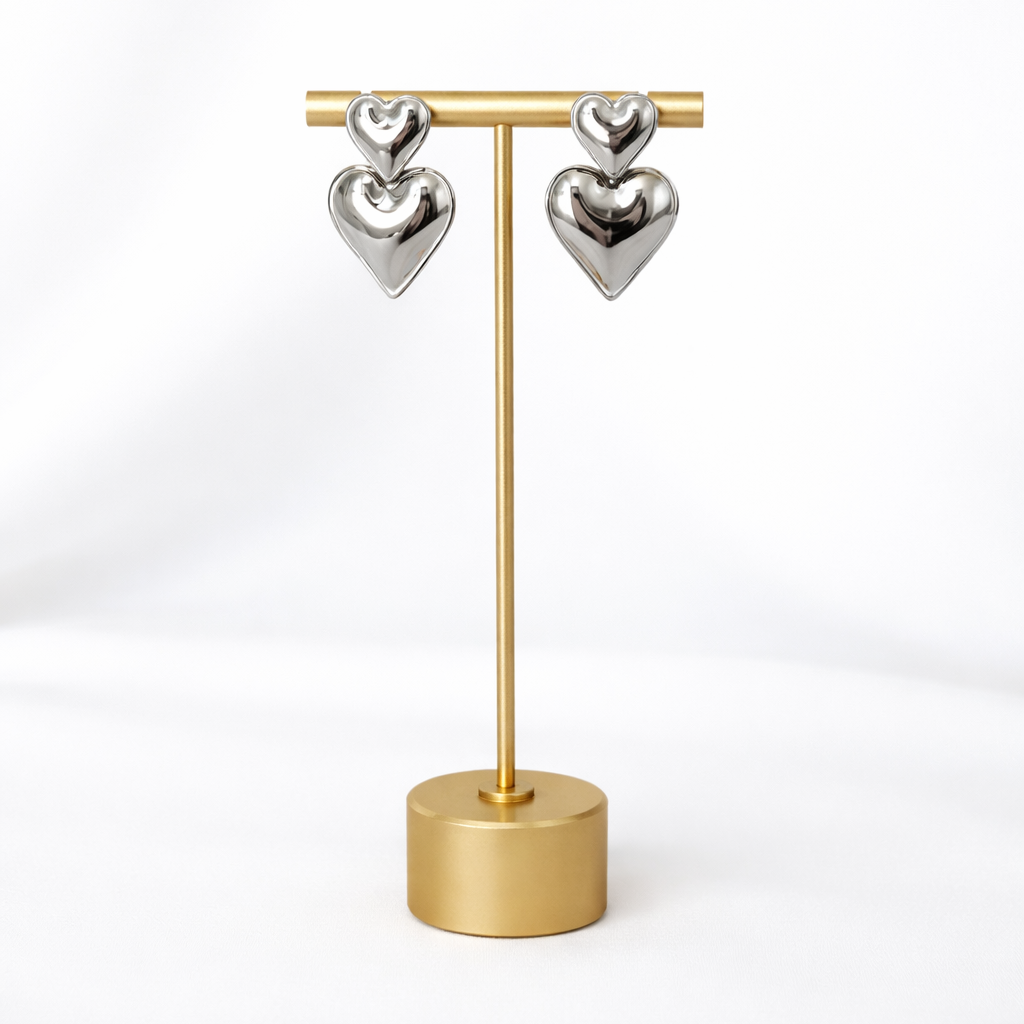Double heart-shaped earrings on a gold stand against a white background