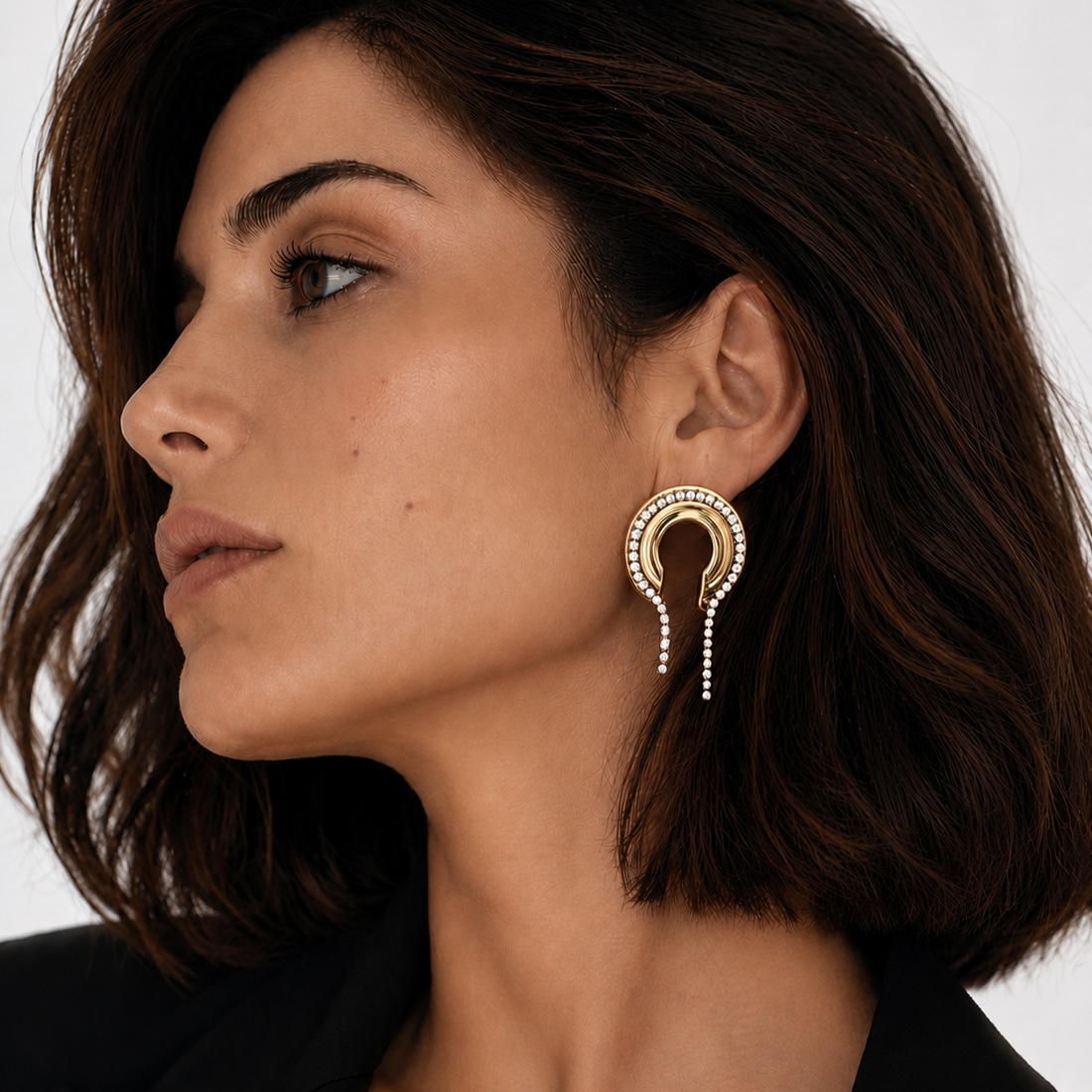 Close-up of a woman wearing a gold plated Lady Lou Collection earring with CZ on a white background