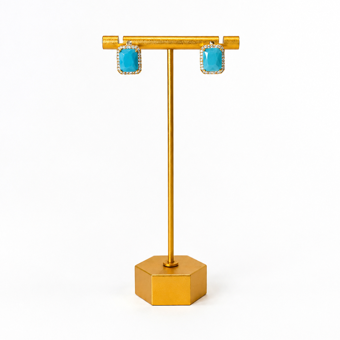 Gold earring stand with turquoise earrings on a white background