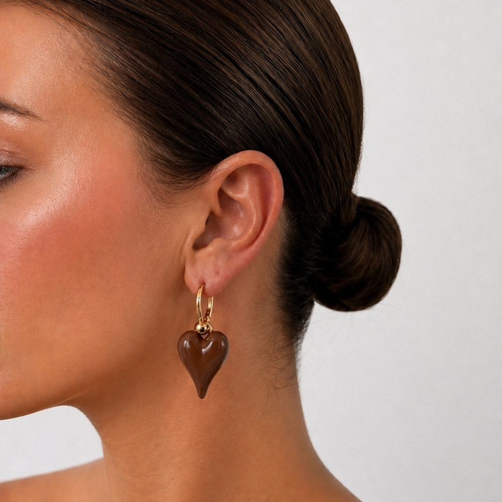 Chocolate Heart-shaped earrings worn by a model with a plain background