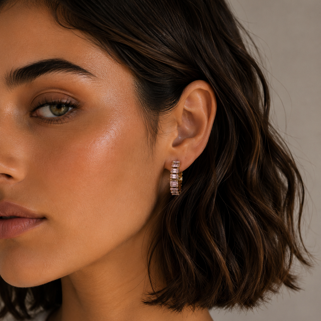Close-up of a woman wearing diamond hoop earrings with a neutral background