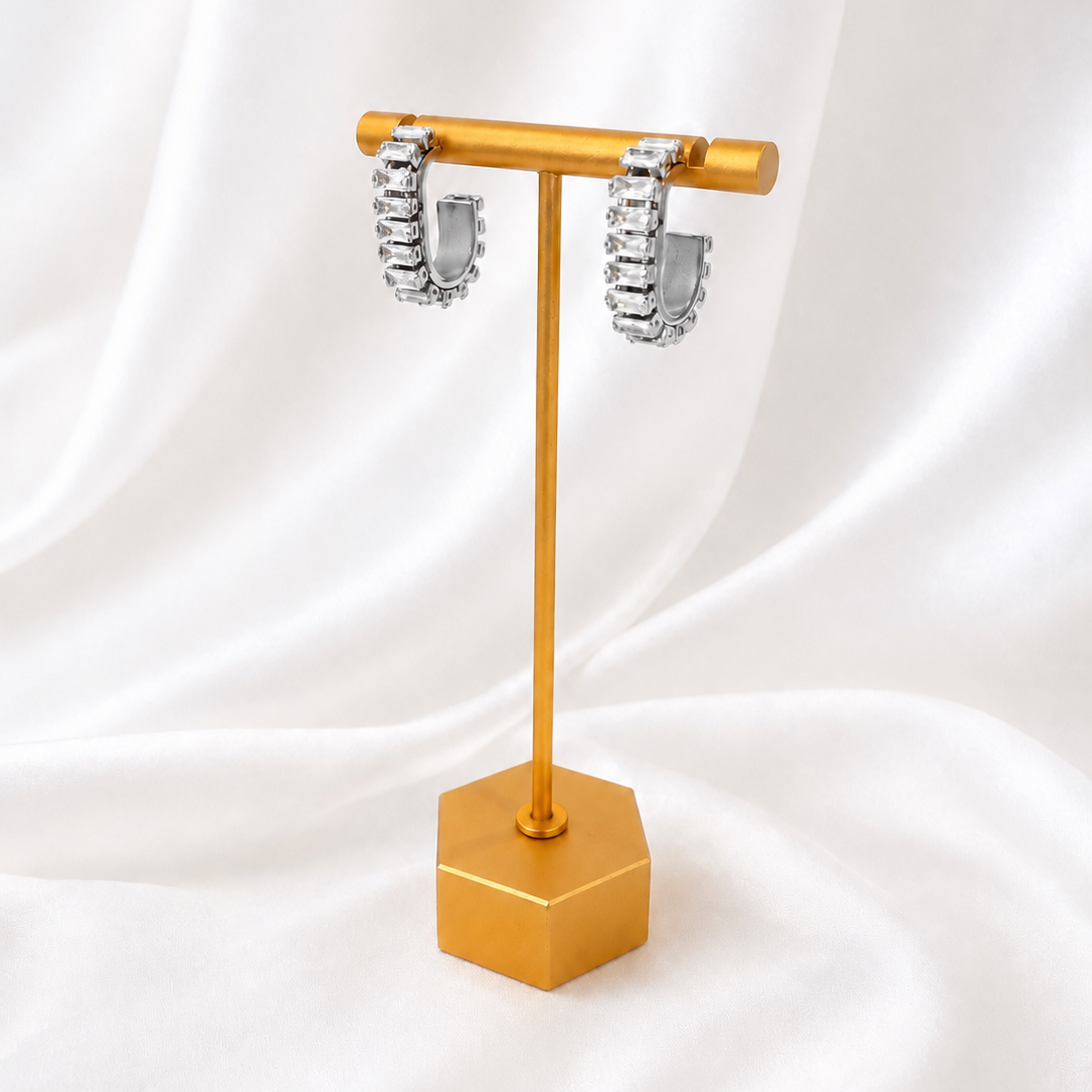 Gold jewelry stand with silver earrings on a white fabric background