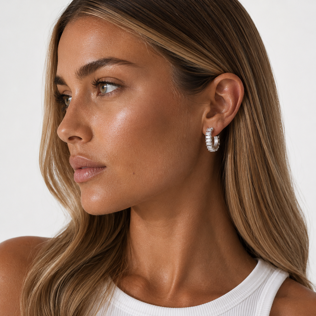 Woman wearing Silver CZ Huggie Earrings with a plain background