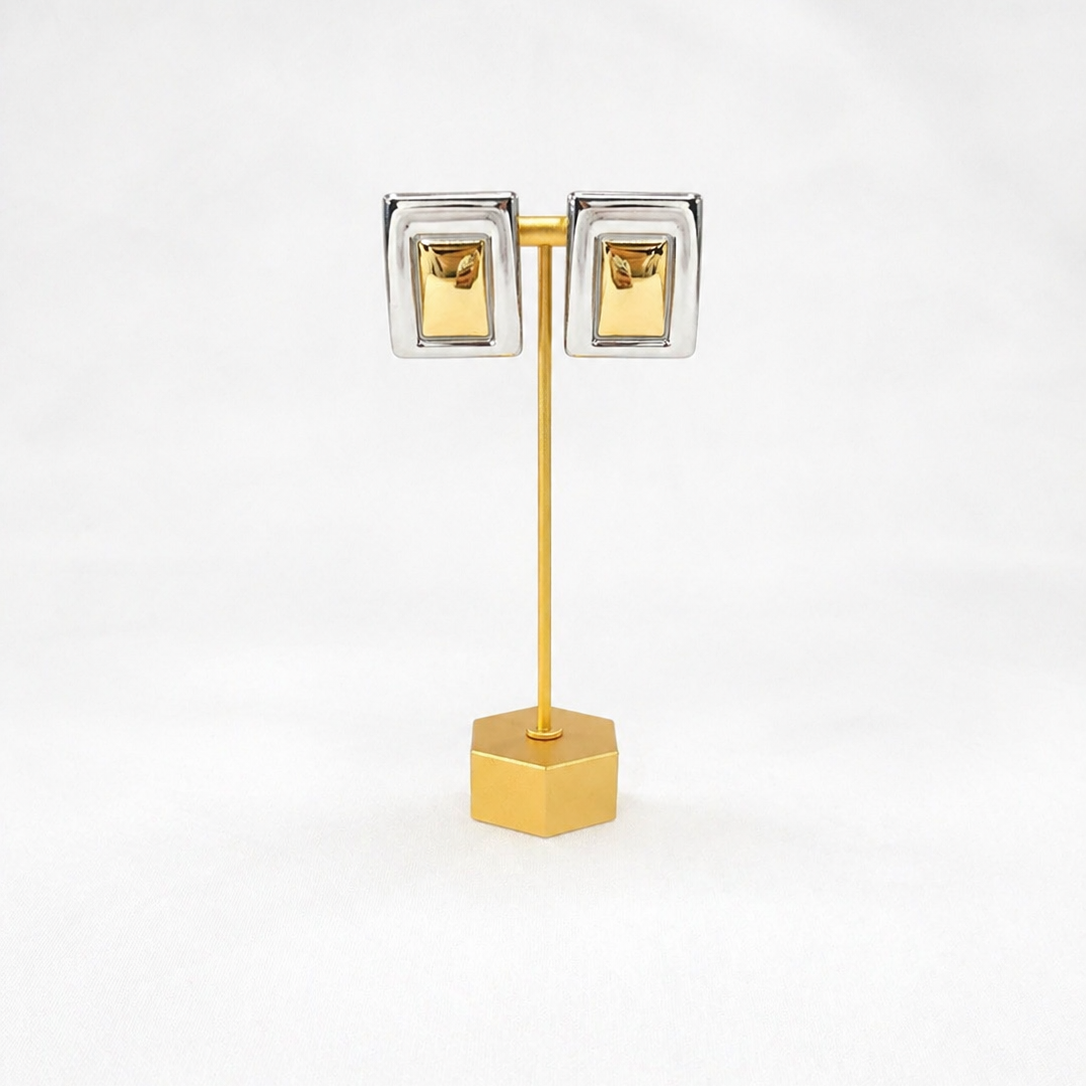 Gold and silver plated earrings on gold stand with white background