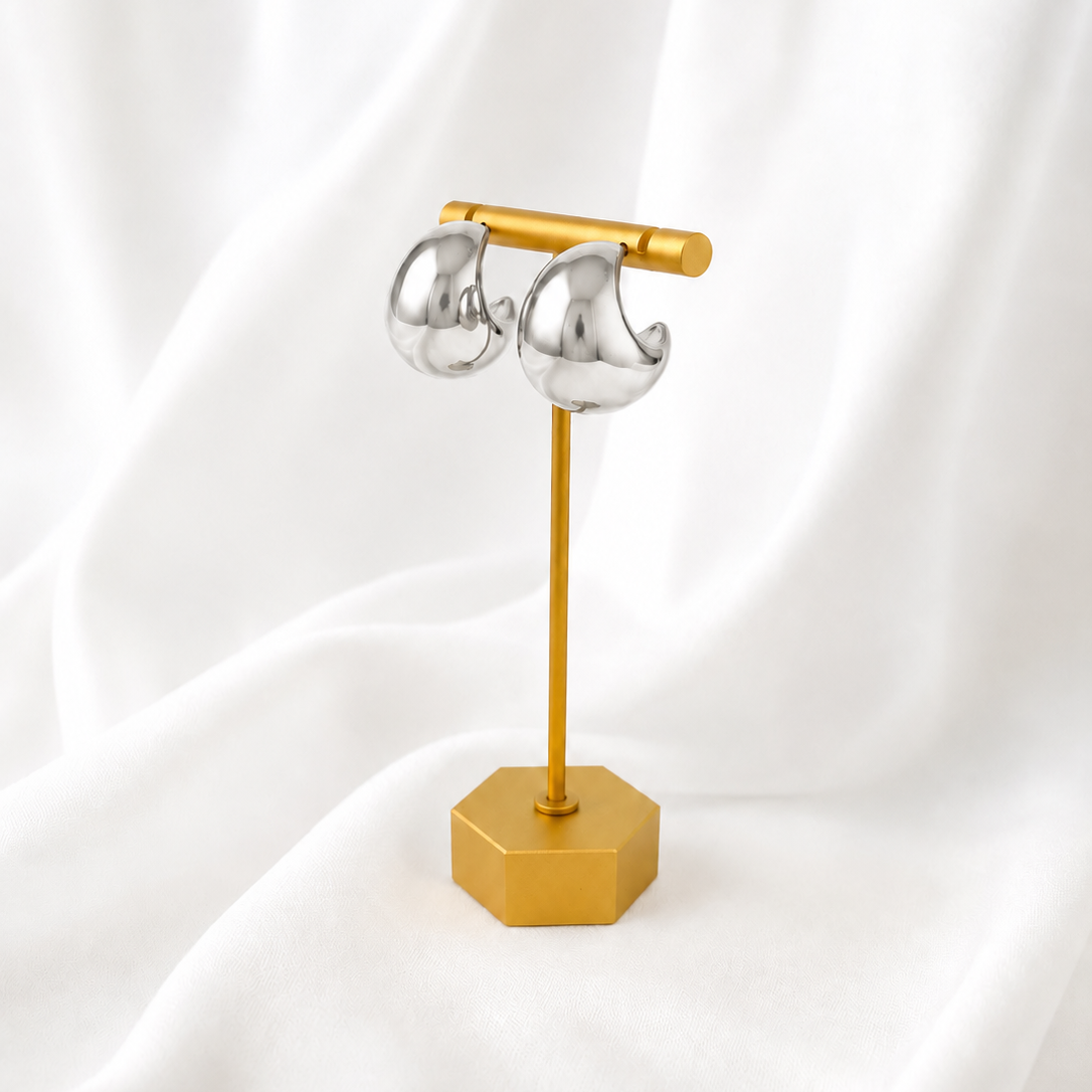 Gold jewelry stand with silver earrings on a white fabric background