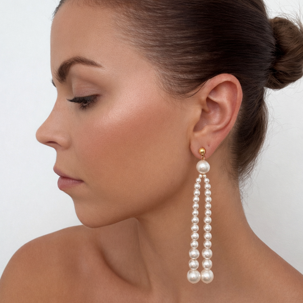Model wearing long pearl drop earrings with gold stud