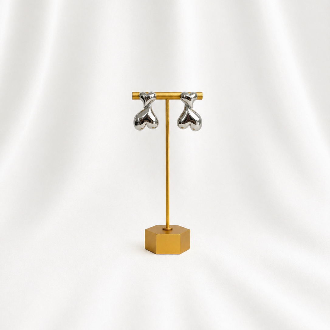 Gold earring stand with silver earrings on a white background