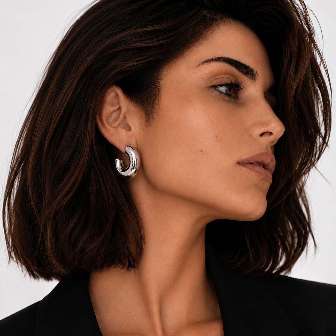 Model wearing silver hoop Lady Lou Collections earrings on white background